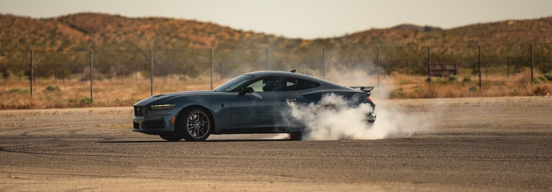 2024 Ford Mustang driving down a dirt lot